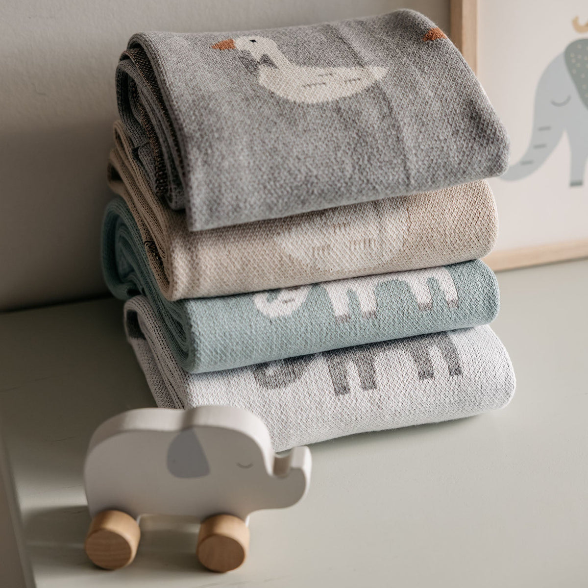 Stack of baby blankets with cartoon designs on a neutral background