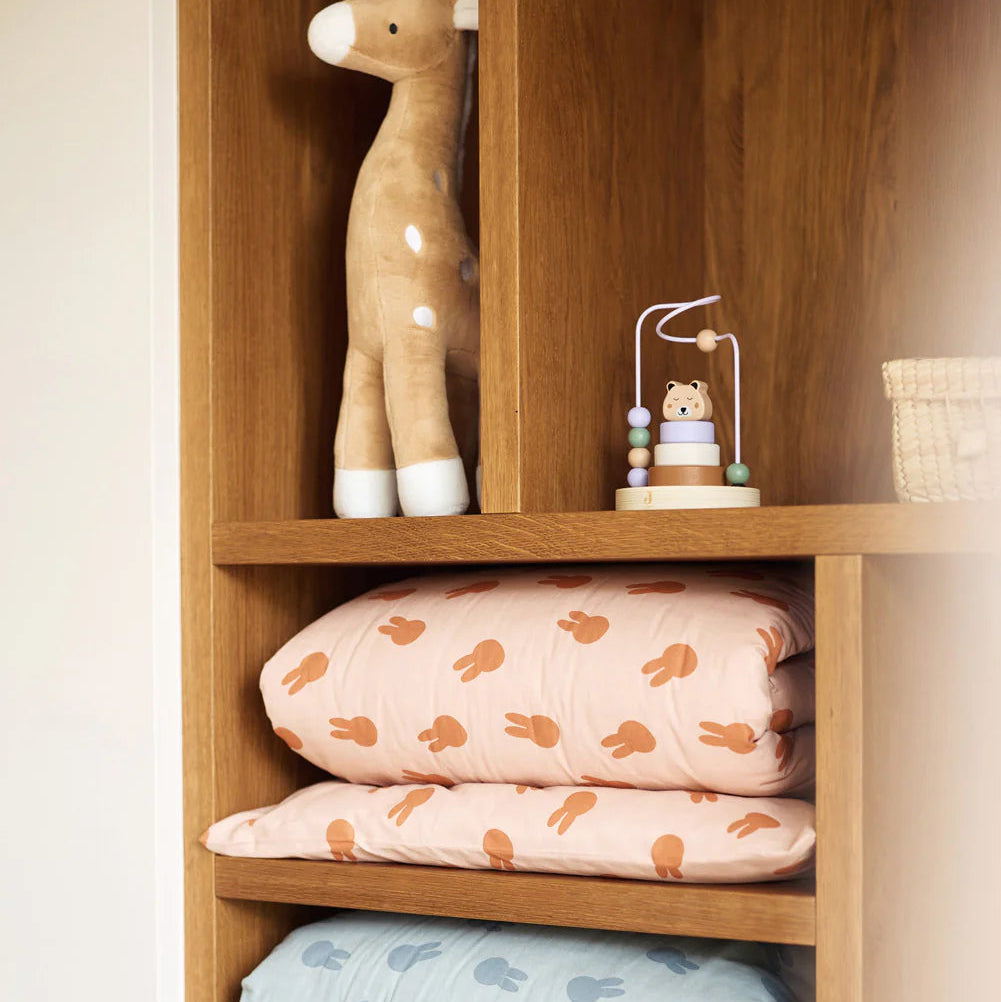 Wooden shelf with baby blankets and toys on a white background
