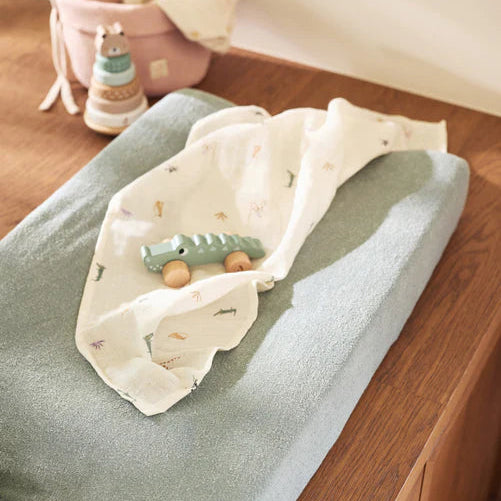 Changing table with a green toy on a wooden surface