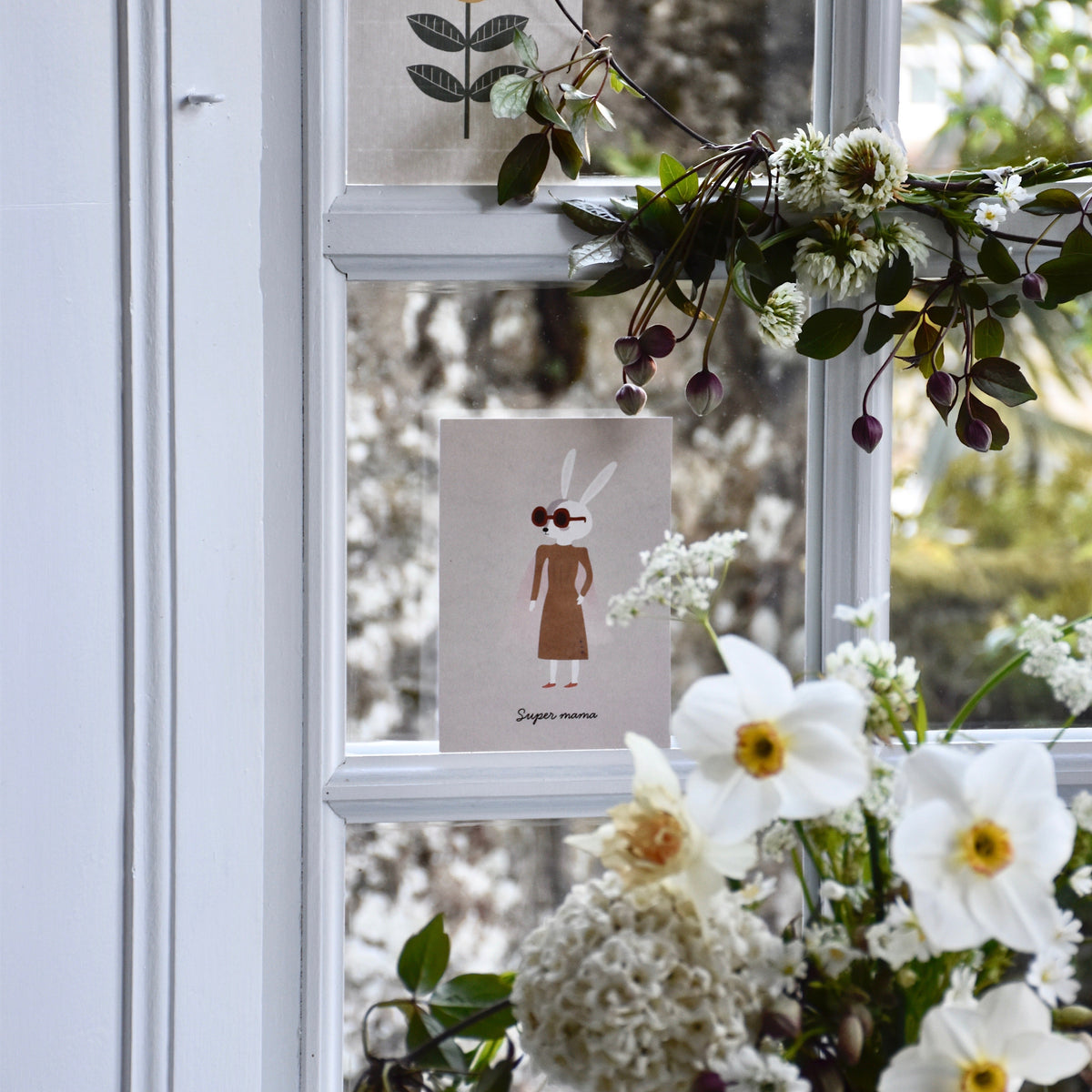 Decorative window with floral arrangements and framed pictures.