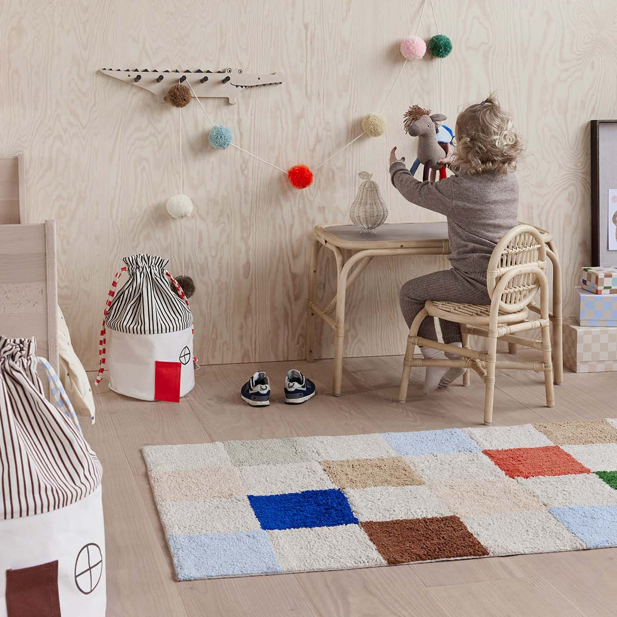 Child playing at a small table in a room with a colorful rug and various toys.