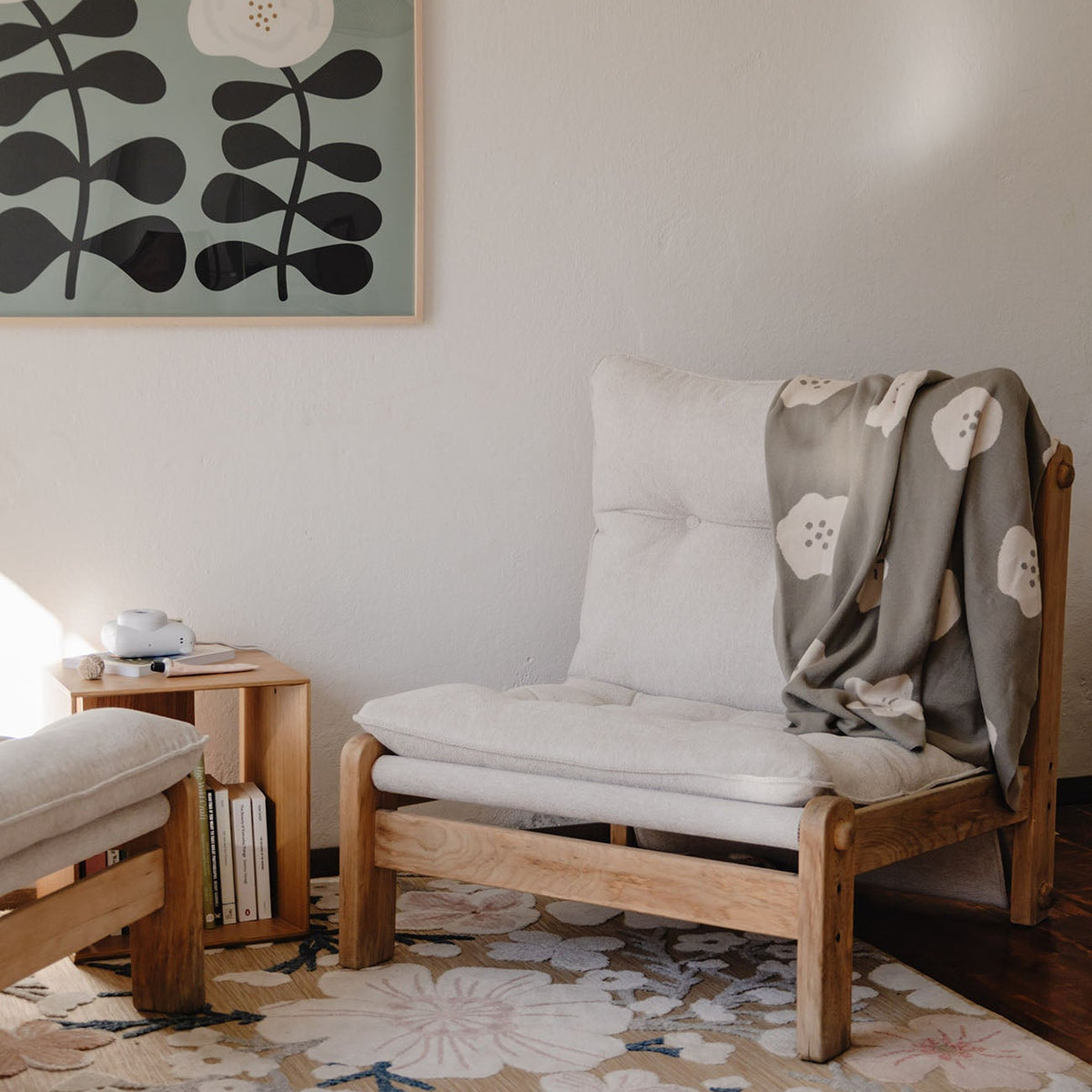 Cozy living room with a wooden chair, floral rug, and abstract wall art.