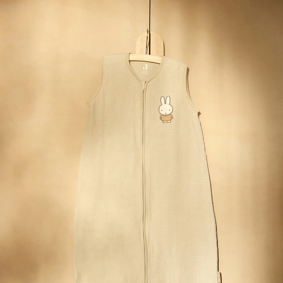 Beige baby sleeping bag with a cartoon character on a beige background 