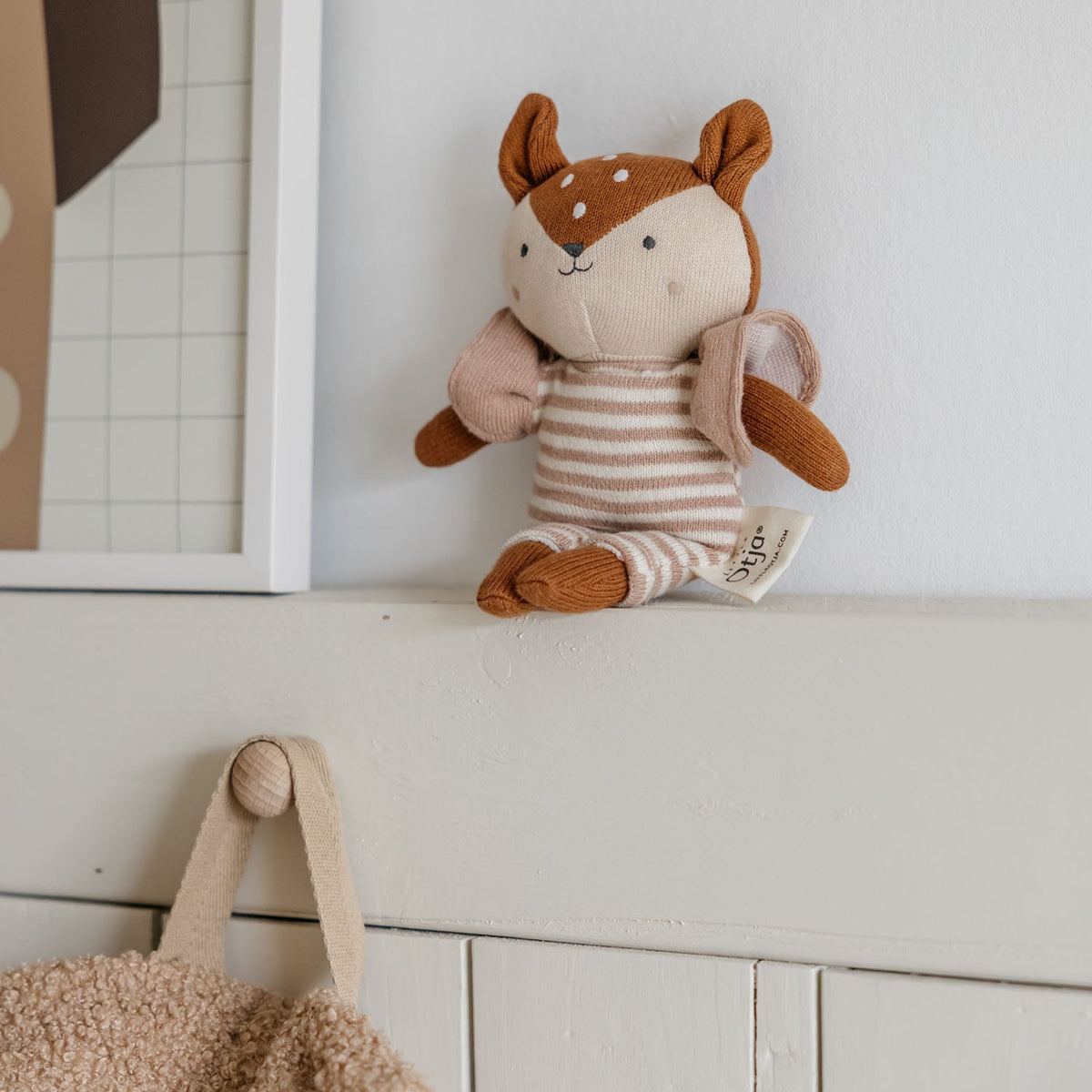 Stuffed animal toy on a shelf next to a framed picture