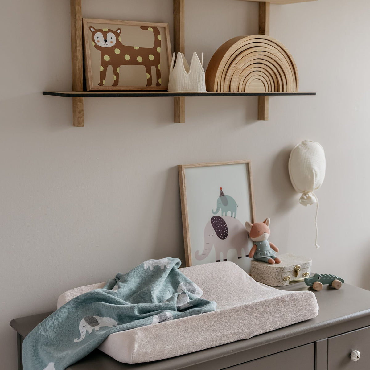 Nursery with wooden shelves, changing table, and decorative items.