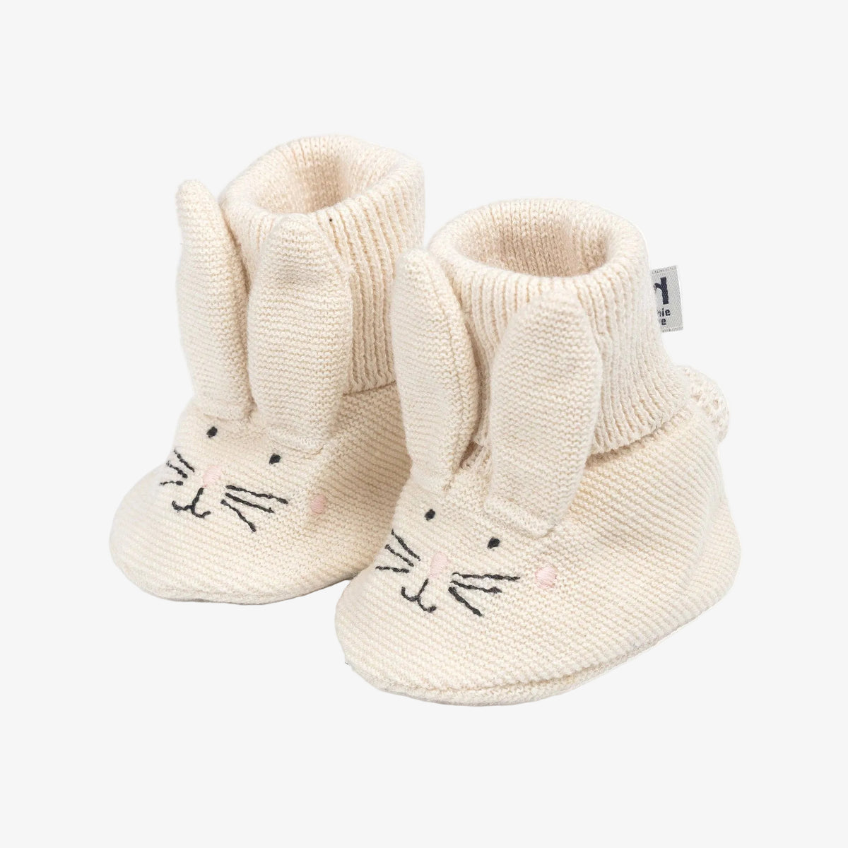 Pair of cream-colored baby booties with bunny design on a white background