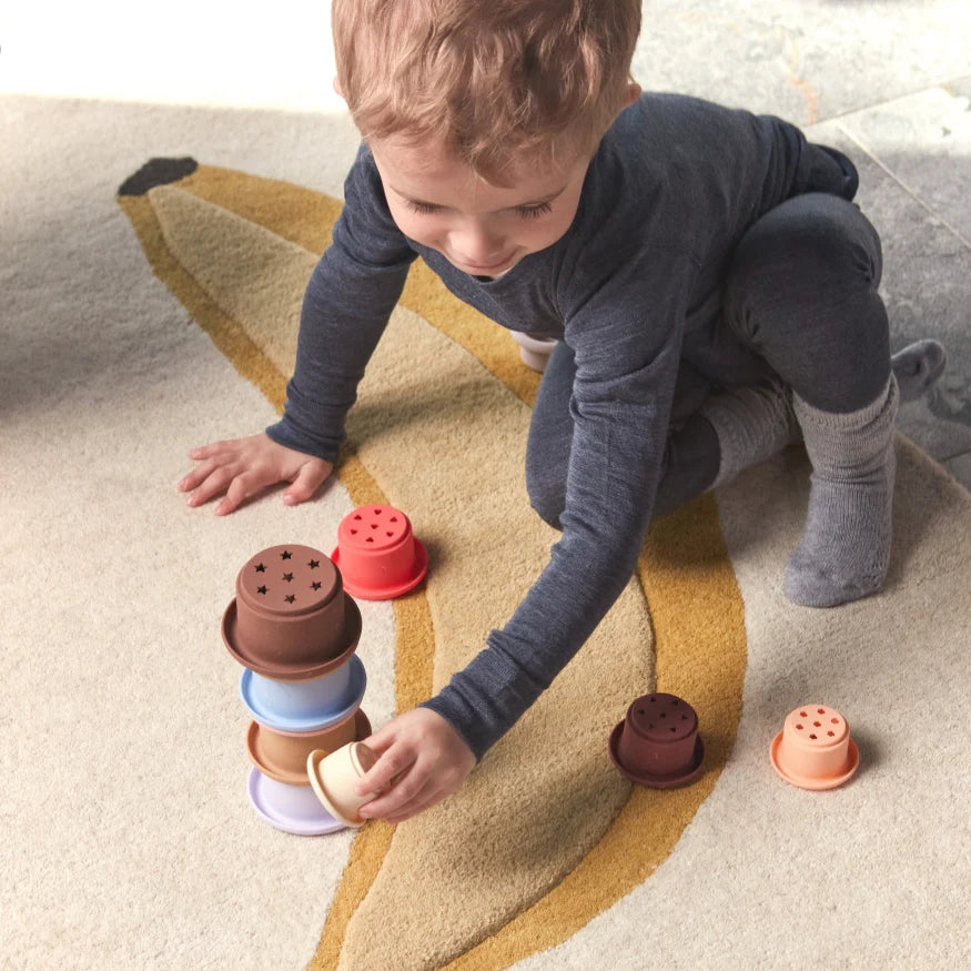 Child playing with colorful stacking toys on a carpeted floor