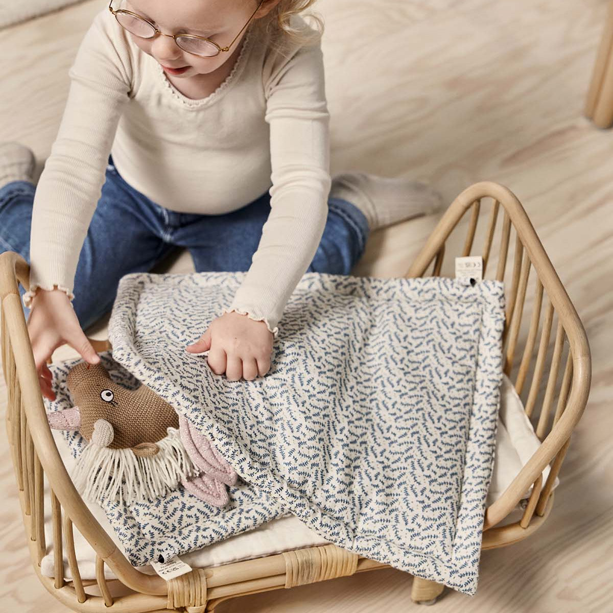 Child playing with a plush toy on a small wooden bed in a cozy room.