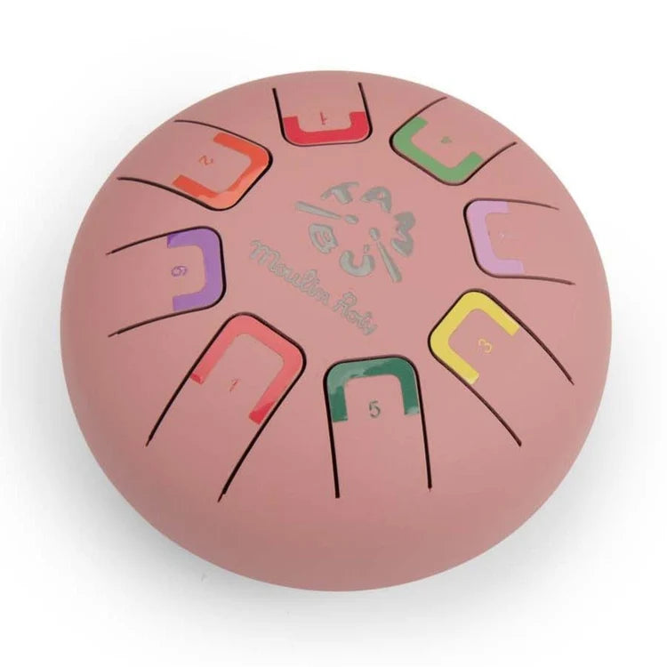 A pink steel pan hand drum with colorful fretboard slots and printed musical note symbols, photographed on a clean white background.